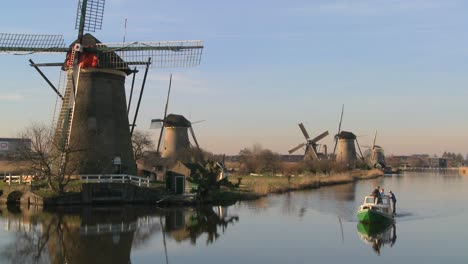 A-boat-moves-along-a-canal-in-Holland-with-windmills-nearby-3