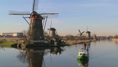 A-boat-moves-along-a-canal-in-Holland-with-windmills-nearby-4