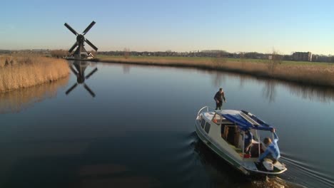 Un-Barco-Se-Mueve-A-Lo-Largo-De-Un-Canal-En-Holanda-Con-Molinos-De-Viento-Cerca-5