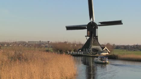A-boat-moves-along-a-canal-in-Holland-with-windmills-nearby-7