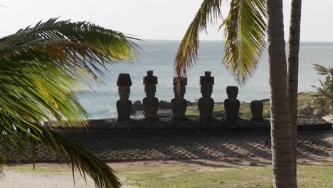 Estatuas-De-La-Isla-De-Pascua-Con-El-Océano-De-Fondo-Y-Palmeras-Ondeando