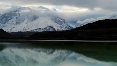 Remarkable-time-lapse-shot-of-clouds-flowing-over-the-mountains-at-Torres-Del-Paine-National-Park-Patagonia-Argentina-with-a-green-lake-in-foreground