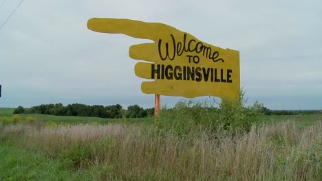 A-large-yellow-sign-points-to-Higginsville-Missouri-from-a-farm-field-1