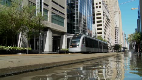 A-rapid-transit-train-moves-quickly-through-downtown-Houston-with-fountains-dancing-3