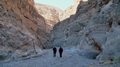 A-senior-man-and-woman-hike-in-a-canyon-in-Death-Valley
