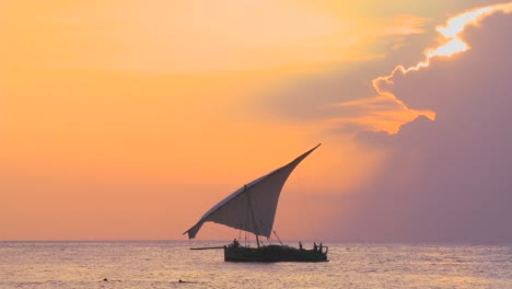 Eine-Schöne-Aufnahme-Eines-Dhow-Segelboots,-Das-Entlang-Der-Küste-Von-Sansibar-Vor-Einem-Wunderschönen-Sonnenuntergang-Segelt
