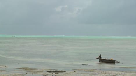 A-distant-native-stands-beside-his-dugout-canoe-in-a-tropical-island-paradise