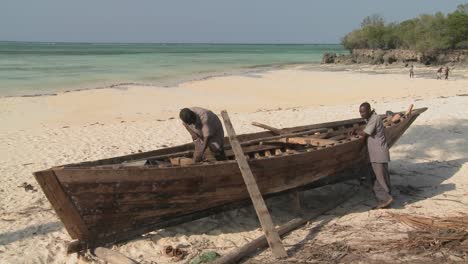 Two-men-work-on-building-a-boat-on-the-coast-of-Zanzibar