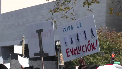 Protestors-hold-signs-at-a-rally-which-include-the-mention-of-tea-baggers-and-evolution