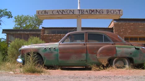 A-slow-moving-shot-tracking-along-an-old-rusted-car-at-an-abandoned-trading-post