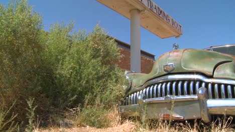 A-slow-moving-shot-tracking-along-an-old-rusted-car-at-an-abandoned-trading-post-1