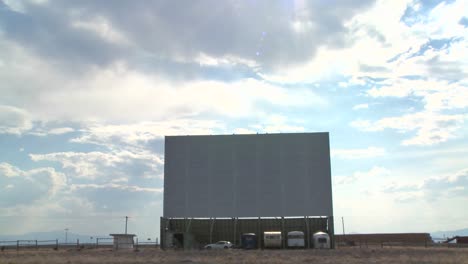 A-time-lapse-shot-of-clouds-passing-over-an-abandoned-drive-in-theater-screen