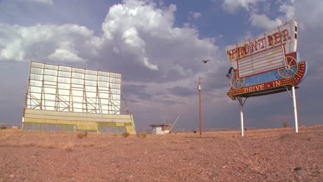 Time-lapse-of-clouds-passing-over-an-abandoned-drive-in-sign-and-screen