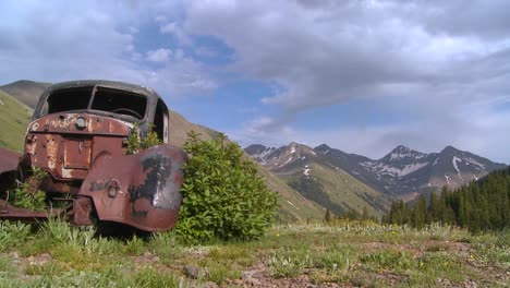 Beautiful-time-lapse-traveling-shot-across-Rocky-Mountains-with-old-abandoned-car-in-foreground
