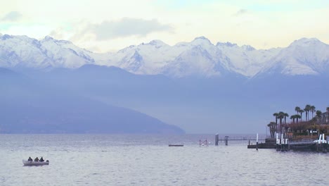 Ein-Fischerboot-Schwimmt-Vor-Einem-Schönen-Kleinen-Italienischen-Dorf-Bellagio-Am-Ufer-Des-Comer-Sees-Mit-Den-Italienischen-Alpen-Im-Hintergrund