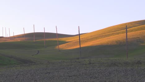 A-solitary-row-of-telephone-poles-stands-against-a-hill