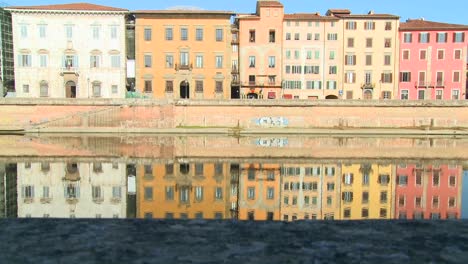 Buildings-line-and-are-reflected-in-a-symmetrical-canal-in-Pisa-Italy