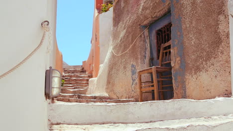 Chairs-sit-in-a-white-and-brown-alley-on-the-island-of-Santorini-in-Greece