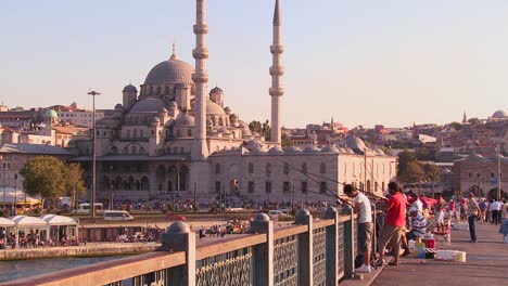 Fishermen-stand-on-a-bridge-in-front-of-the-mosques-of-Istanbul-Turkey-at-dusk