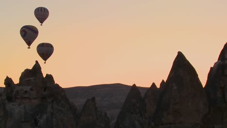 Three-hot-air-balloons-are-beautifully-silhouetted-against-a-mountain-peak-in-Cappadocia-Turkey
