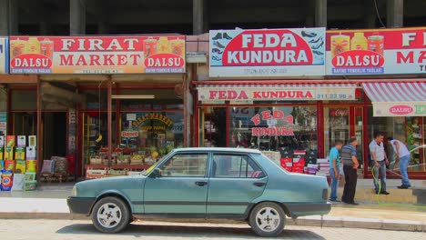 Car-is-parked-in-front-of-colorful-shops-and-signs-in-a-remote-town-in-central-Turkey