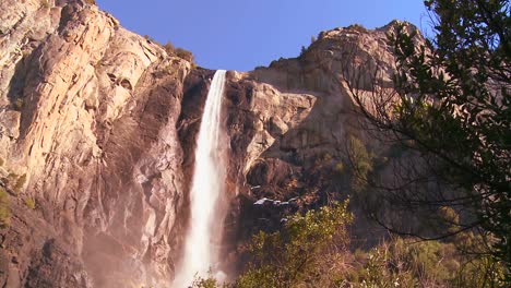 Flachwinkelschwenk-über-Einen-Wunderschönen-Wasserfall-Im-Yosemite-Nationalpark,-Während-Er-Einen-Regenbogen-Wirft-1