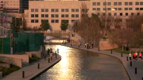 Zoom-out-from-Indianapolis-Indiana-río-walk-at-dusk-with-sun-glinting-off-buildings