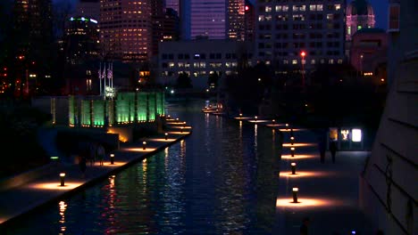 Tilt-up-to-the-city-of-Indianapolis-Indiana-at-night-with-the-White-River-foreground