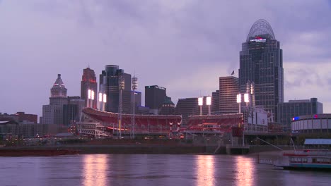 Die-Nacht-Fällt-über-Cincinnati,-Während-Flussboote-Den-Ohio-River-Passieren