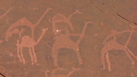 Close-up-of-ancient-and-mysterious-petroglyphs-depicting-humans-and-camels-in-the-Saudi-desert-near-Wadi-Rum-Jordan