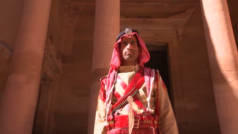 Tilt-down-to-Bedouin-warrior-standing-in-front-of-the-facade-of-the-Treasury-building-in-the-ancient-Nabatean-ruins-of-Petra-Jordan