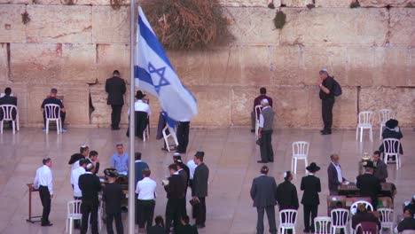 Die-Israelische-Flagge-Weht-Vor-Jüdischen-Pilgern,-Die-An-Der-Klagemauer-In-Jerusalem-Beten