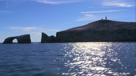 Weite-Aufnahme-Der-Insel-Anacapa-Mit-Ihrem-Leuchtturm-Und-Der-Ikonischen-Natürlichen-Brücke,-Die-Von-Einem-Sich-Nähernden-Boot-Aus-Gesehen-Werden-Kann