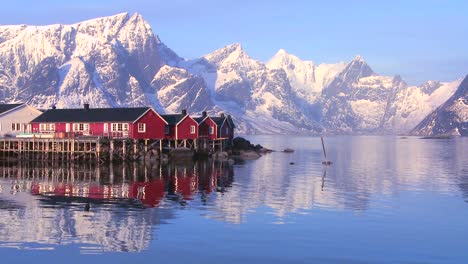 Snowcapped-peaks-loom-behind-a-red-fishing-village-in-the-Arctic-Lofoten-Islands-Norway-2