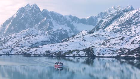 A-fishing-boat-heads-through-fjords-in-the-Arctic-on-glassy-green-water-in-the-Lofoten-Islands-Norway-2