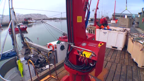 Traveling-shot-of-fishermen-unlading-trawlers-on-a-dock-in-Norway