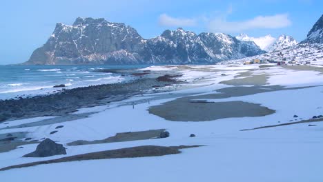 Las-Olas-Ruedan-Hacia-Una-Hermosa-Playa-Cubierta-De-Nieve-En-Medio-De-Los-Fiordos-Al-Norte-Del-Círculo-Polar-ártico-En-Las-Islas-Lofoten,-Noruega