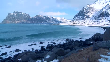 Waves-roll-into-a-beautiful-snow-covered-shoreline-amidst-fjords-north-of-the-Arctic-Circle-in-Lofoten-Islands-Norway