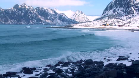 Waves-roll-into-a-beautiful-snow-covered-shoreline-amidst-fjords-north-of-the-Arctic-Circle-in-Lofoten-Islands-Norway-1