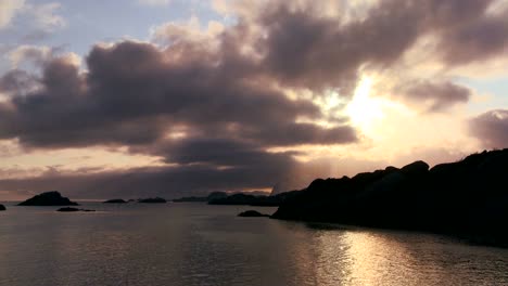 Time-lapse-of-golden-sunset-clouds-behind-a-shoreline-amidst-fjords-north-of-the-Arctic-Circle-in-Lofoten-Islands-Norway