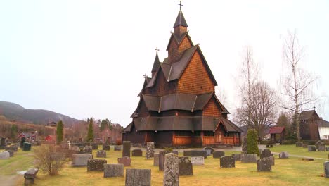 Wide-shot-of-a-cemetery-in-front-of-an-old-wooden-stave-church-in-Norway