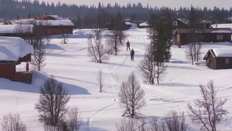 Cross-country-skiers-follow-a-trail-through-a-village-in-Norway