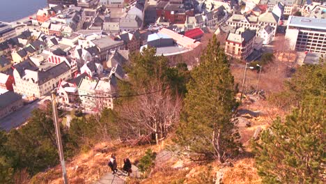 Ein-Jogger-Läuft-Einen-Hügel-Hinunter-Aus-Einem-Hohen-Blickwinkel-über-Die-Stadt-Alesund-Norwegen