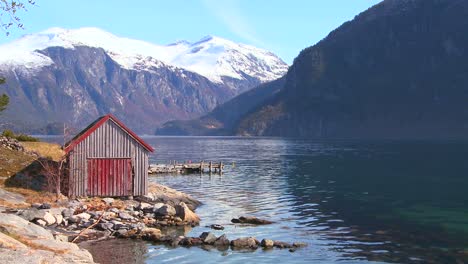 Beautiful-wide-shot-of-the-fjords-of-Norway-with-weathered-red-boathouse