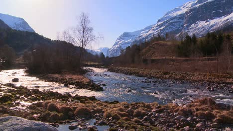 A-beautiful-río-runs-through-a-snowy-fjord-in-Norway