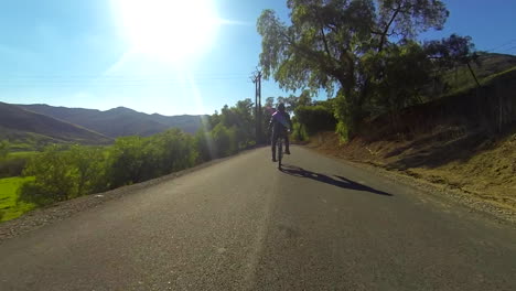 Un-Hombre-Monta-Una-Bicicleta-Motorizada-Por-El-Campo-En-Una-Carretera-De-Dos-Carriles-6