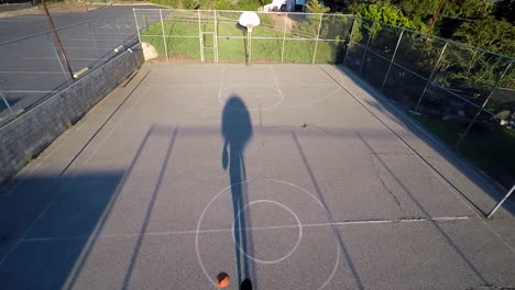 Eine-Vogelperspektive-über-Einen-Basketballspieler,-Der-Auf-Einem-Außenplatz-Dribbelt