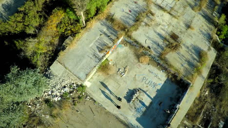 Aerial-shot-of-teenage-boys-skateboarding-in-the-graffiti-covered-foundation-of-an-abandoned-building-6