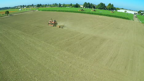 An-aerial-over-a-a-farm-worker-driving-a-tractor-across-barren-fields