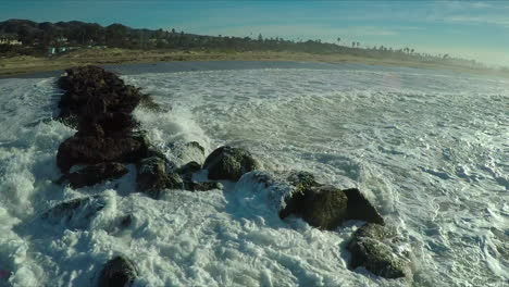 Aerial-over-a-generic-California-coastline-with-big-waves-rolling-in-and-breaking